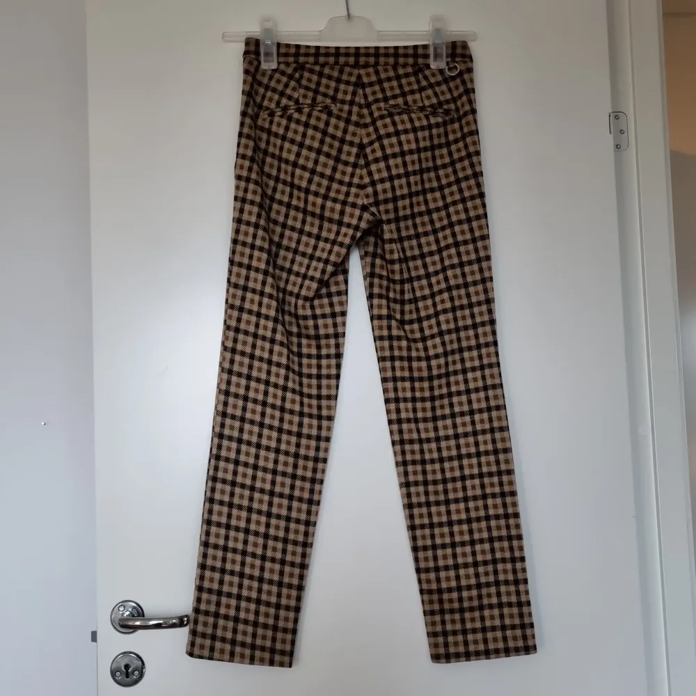Ett par snygga bruna byxor med rutigt mönster. Tyget är mjukt och bekvämt. De har ganska små fickor på framsidan och fickorna på baksidan är fake. Nypris: 599 kr. Jeans & Byxor.