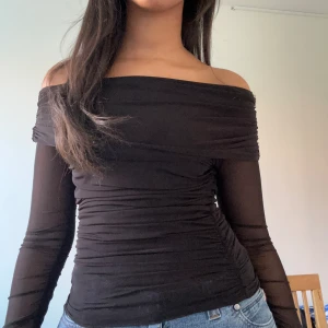 Svart off-shoulder topp - Snygg off-shoulder med mesh-material. Slits på ärmarna också! Så snygg för alla tillfällen! 
