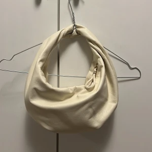 Vit handväska - Benvit handväska med innerficka💘 Köpt i en spansk accessoar-butik så inte helt säker på märket men orginalpriset var 20 euro. Använd nån enstaka gång, enda tecken på användning är en liten klick rött nagellack innuti😅Ca 21cm djup & ca 33cm ”lång”