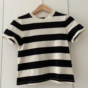 En beige svart randig t-shirt ifrån Lindex. Tröjan är i en väldigt snygg modell och lite kortare än en ”vanlig” t-shirt. Endast använd 2 gånger, så i bra skick🥰😍💗💘