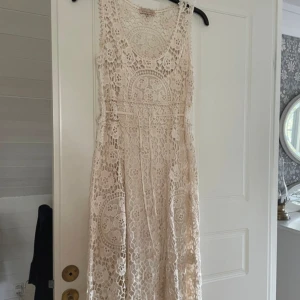 Virkad klänning  - Sparsamt använd. Tyvärr har ena snöret gått av så jag har gjort en Knut, se bild. Annars fint skick.