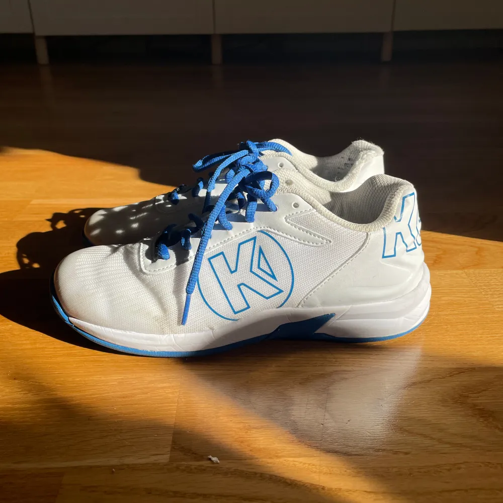 Säljer dessa blå och vita handboll skor i bra skick. Skorna är i storlek 39 och ena skorn har en skada längst bak.. Skor.