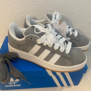 Nya Adidas Campus 00s -storlek 37 1/3 - Adidas Originals Campus 00 s j Storlek: 37 1/3 (stor) Innersulan är 24,2 cm Färg: Gråa (Grey Three / Cloud White / Cloud White) Ingår både vita och gråa skosnören.  Nya och oanvända. Ligger kvar i kartong. 