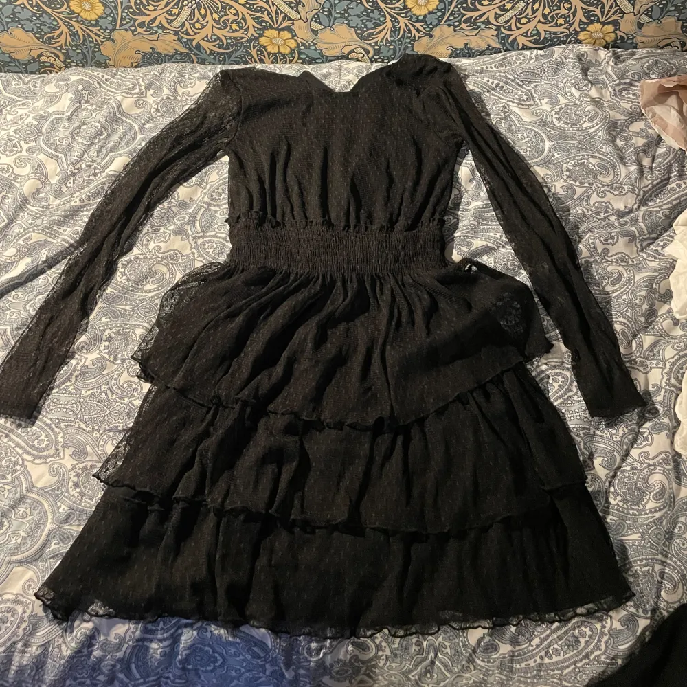 Det är en svart klänning i polyester med lite volang i bra skick. Klänningar.