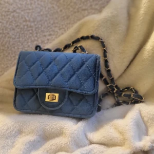 Söt blå axelbandsväska - Söt axelbandsväska i mjukt, ljusskimmrande material. Låsknappen är skavd men annars hel