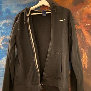Svart Nike Zip Up Hoodie - Skön Nike zip up i storlek M, använd några gånger och köpt för 500kr. Gjord för killar men funkar lika bra på tjejer!💕