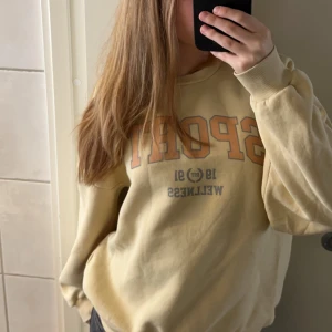 Sweatshirt - En gul sweatshirt ifrån Gina tricot med texten ”Sport, 1991, Wellness” skrivet på framsidan. Superfint skick. Storlek L men passar mig som vanligtvis har M. Skriv privat vid frågor 💓