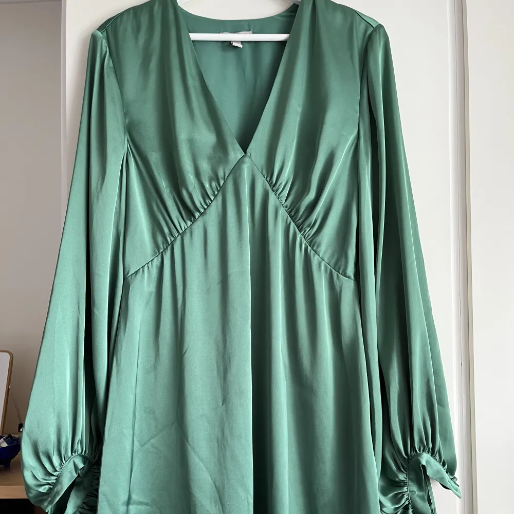 Smaragdgrön satinklänning med stora ballongärmar. Klänningen är ganska kort, typ mitt på låret på mig som är knappt 170 cm lång. Väldigt vackert fall! Använd en gång. . Klänningar.
