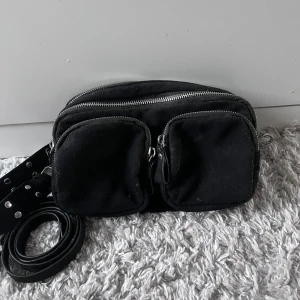 Väska - Säljer denna fina svarta väska från Gina som tyvärr inte kommer till användning längre! Den har några små fläckar som knappt syns i verkligheten (går säkert bort i tvätten). Annars i bra skick, man får med ett längre och ett kortare band💓