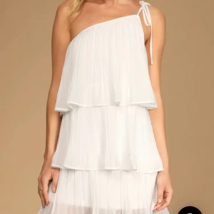 Vit student klänning / konfa - Säljer denna jätte snygga helt nya med lapp kvar studentklänning från lulus💓priset går att diskuteras. Nypris: 859kr (+tull)🩷Blowing Kisses White Pleated One-Shoulder Mini Dress