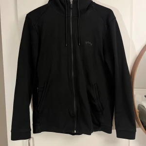 Hugo Boss Zip Hoddie  - Svart Hugo Boss kofta. Kofta är i ny skick och nästan helt orörd. Säljer den för att den inte kommer till användning.