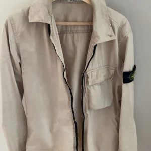 Stone island overshirt - Säljer en mycket snygg beige Stone island overshirt perfekt till sommarkvällar. Sparsamt använd så skick 8/10 och storlek S