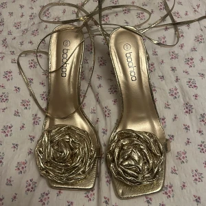 Guldiga klackar  - Guldiga klackar med ros, aldrig använda. Storlek 38!