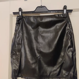 Svart "läder" kjol  - Aldrig använd Läder imitation Liten slit framtill Dragkedja på sidan