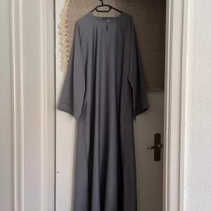 Säljer denna grå/blåa abaya i storlek 60 från Luudecollection. Använd men fortfarande i bra skick. Det finns dock sminkfläckar vid halsen som inte gått bort i tvätten, samt en fläck vid ärmen som syns på bilden. Köpt för 400 kr, säljes för 200 kr.
