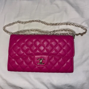 Rosa väska  - Rosa väska som liknar Chanel. Axelremsväska.  Axelrem som kan vikas dubbelt så att den blir kortare.  Färgen har börjat släppa
