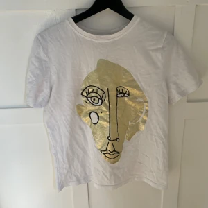 T-shirt  - T-shirt med guldigt tryck. Mycket fint skick.