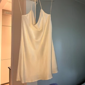 Slipdress - Kort vit satin klänning från Zara. Faller fantastiskt runt höfter och midja. Snygg att stylea med ett par färgade sneakers eller fina klackar. Går att klä upp med smycken och att klä ned med en snygg hoodie över. 