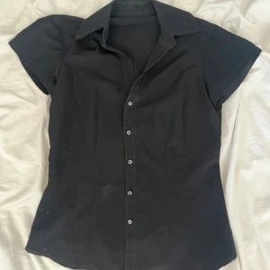 Kort ärmad skjorta  - Svart kort ärmad skjorta, figursydd. Köparen står för frakt.