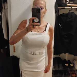 Vit klänning med skärp i midjan - Ni har köpt vit klänning med skärp i midjan med dragkedja i ryggen och slits på sidan storlek 38