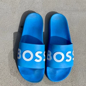 Hugo boss badtofflor  - Riktigt snygga badtofflor i din blå färg. Tofflorna är använda men är i fint skick. Strlk 43.