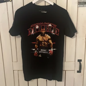 Dynamike Mike Tyson T-shirt  - Riktigt fet Mike Tyson tröja som har blivit tyvärr för liten. Den har inga skavanker eller något så den är ändå 8/10 i skick. Den är i storlek S , köptes för ca ett år sedan.