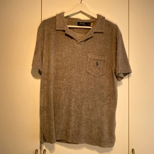 Ralph Lauren frotté pike Grå - Hej, säljer en grå frotté pike från Polo Ralph Lauren. Använd men i fint skick. Nypris 1900kr på care of Carl. Storlek M. Passar perfekt för sommaren & varmare väder. Lätt att stylea, perfekt till linnebyxor. Pris kan diskuteras. Hörs i DM! 