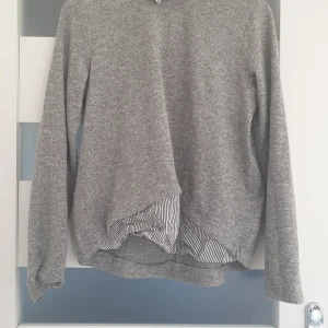 En grå tröja - En grå tröja men en skjorta under.