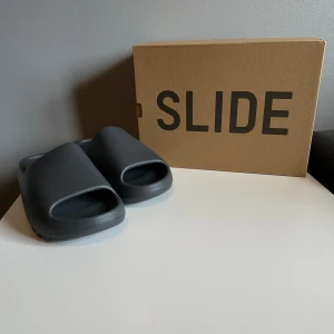 Yeezy Slide  - Säljer ett par Teezy Slide i färgen ”slate grey”. De är helt oanvända och jag köpte dem ifrån CONFIRMED förra året. Mer info, bilder och kvitto privat.