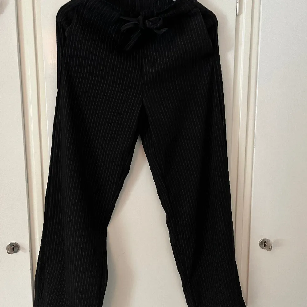 Snygga svarta kostymbyxor med vita tunna ränder. Använda flertal gånger men är i nyskick.. Jeans & Byxor.