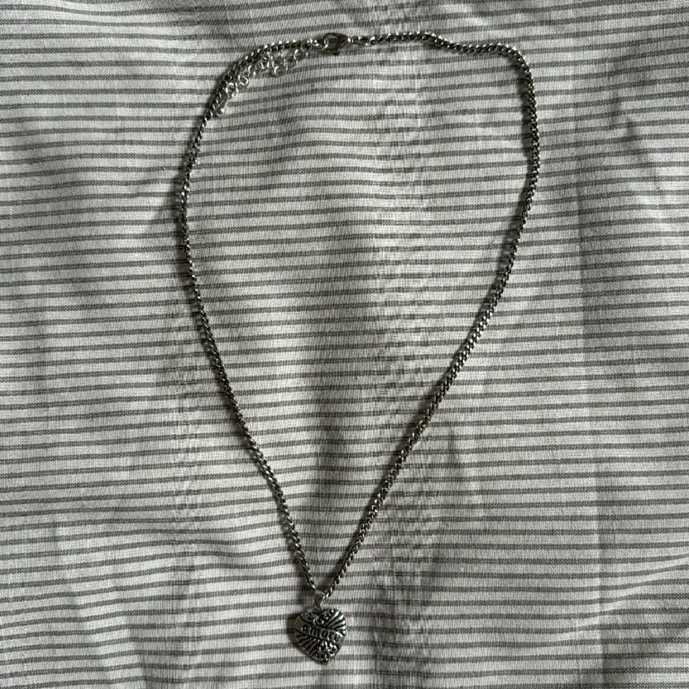Halsband med ett hjärta där det står ”amore” Justerbar längd. Ganska kort kedja. 100% zink.. Accessoarer.