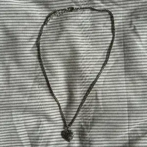 Halsband med ett hjärta där det står ”amore” Justerbar längd. Ganska kort kedja. 100% zink.