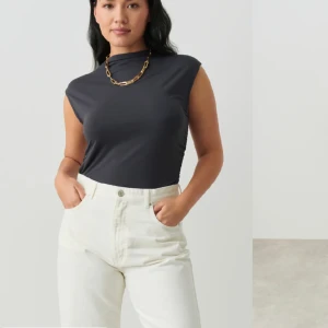 Topp med rynkningar i sidan - Mörkgrå topp från Gina tricot, hög i halsen och med rynkningar i sidan 🥰 Bild på den gröna modellen är bara för att visa hur rynkningarna ser ut på sidan ☺️ Endast använd två gånger. 