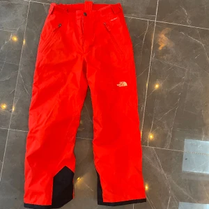 The north face skidbyxa för junioren - Fint skick, härligt orange färg.  Stl junior M (motsv ca 140 cm).  Funktionsbyxa/skalbyxa med tunt isolerande foder. Smidiga i backen!
