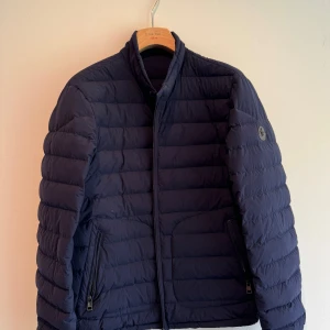 Marinblå Moncler lightweight jacka - Marinblå Moncler Doudoune Elastique  En tunn och mycket lätt dunjacka från Moncler. Fickor med dragkedja. Jackan är bara använd ett fåtal gånger - nyskick.  Storlek 4 Classe 1 dun