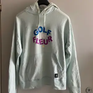 En bekväm ljusblå hoodie från GOLF le FLEUR x Converse i blått, rosa och lila på framsidan