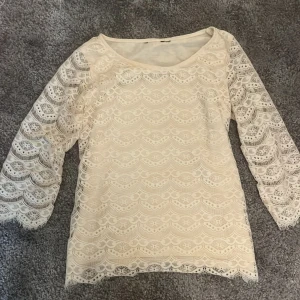 En vit blus med genom skinade armar och mönster - Storleken står inte men gissar att den är i storlek s