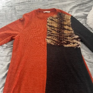 Tröja  - Säljer denna unika tröja! Den är orange vid halva sidan och svart vid den andra halva sidan samt med dekoration på den svarta sidan vid bröstet! 