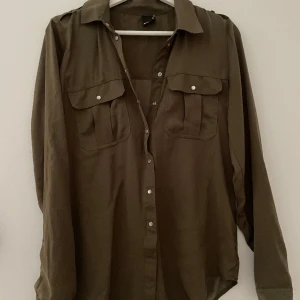 Grön blus med fickor  - Blus i väldigt skönt material, knytning nere vid ändarna 