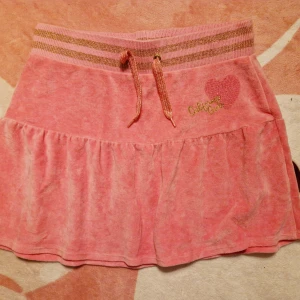 Rosa plisserad sammet kjol med tryck  - Stretchig midja som går att spänna till. Står california girl på den