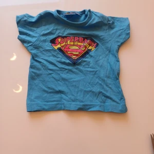 T-shirt  - T-shirt "superbaby" med knappar på sidan. Väldigt fint skick 