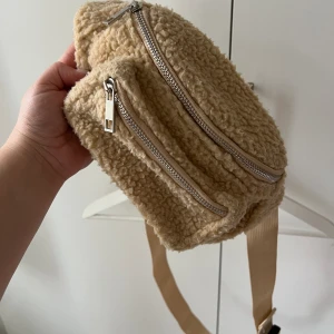 Crossbody väska teddy - En beige crossbody väska i teddymaterial. Justerbart band. Två fack med dragkedjor. Använd ett fåtal gånger, bra skick. 