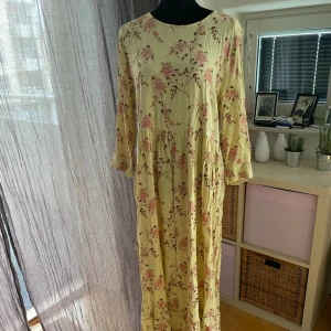 Klänning strl 40 Ginatricot  - Fin långklänning i strl 40 Från Ginatricot  Gul med rosa aktiga blommor Använd en gång så nyskick 