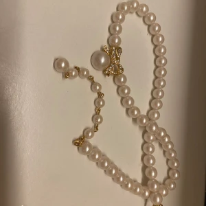 Jättevackert pärlhalsband med rosett - Superduper fint pärlhalsband med en guldig rosett berlock