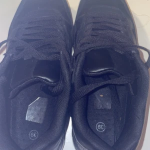 Svarta sneakers i storlek 39 - Säljer ett par svarta sneakers i storlek 39. De är i bra skick och har snörning. Perfekta för vardagsbruk och passar till det mesta. Köp direkt eller ge prisförslag!