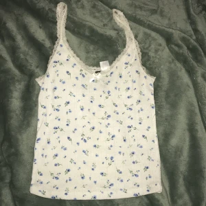 vit linne med blåa blommor - säljer detta jättesöta linne med blå blommor från h&m divied. Den har spets o en liten rosett längst fram. Storlek xxs💕