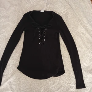 Svart tröja - En svat ribbad tröja från gina som är i ett fint skick. Inte använd så mycke så de finns inga skador, de ända som är de är bara snörena som är lite snurrade men de går lätt att fixa!