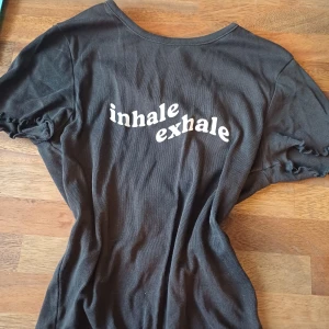 Svart t-shirt med texten 'inhale exhale' - Svart t-shirt med text. Gjord av bomull och har korta ärmar och en ribbad kant vid ärmslut och nederkant. 🖤🤍