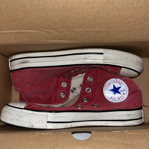 Röda Converse All Star sneakers - Säljer ett par röda Converse All Star sneakers i storlek 37,5. Skorna är välanvända men fortfarande i bra skick. De har den klassiska vita sulan med svart rand och Converse-loggan på sidan. Perfekta för en avslappnad och cool stil!