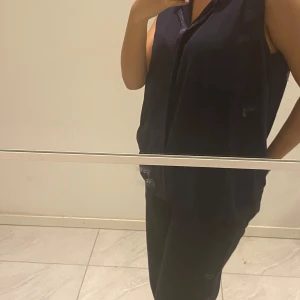 Mörkblå ärmlös blus - En mörkblå ärmlös blus med en enkel design. Blusen har en lös passform och är tillverkad i ett lätt material, vilket gör den bekväm att bära.